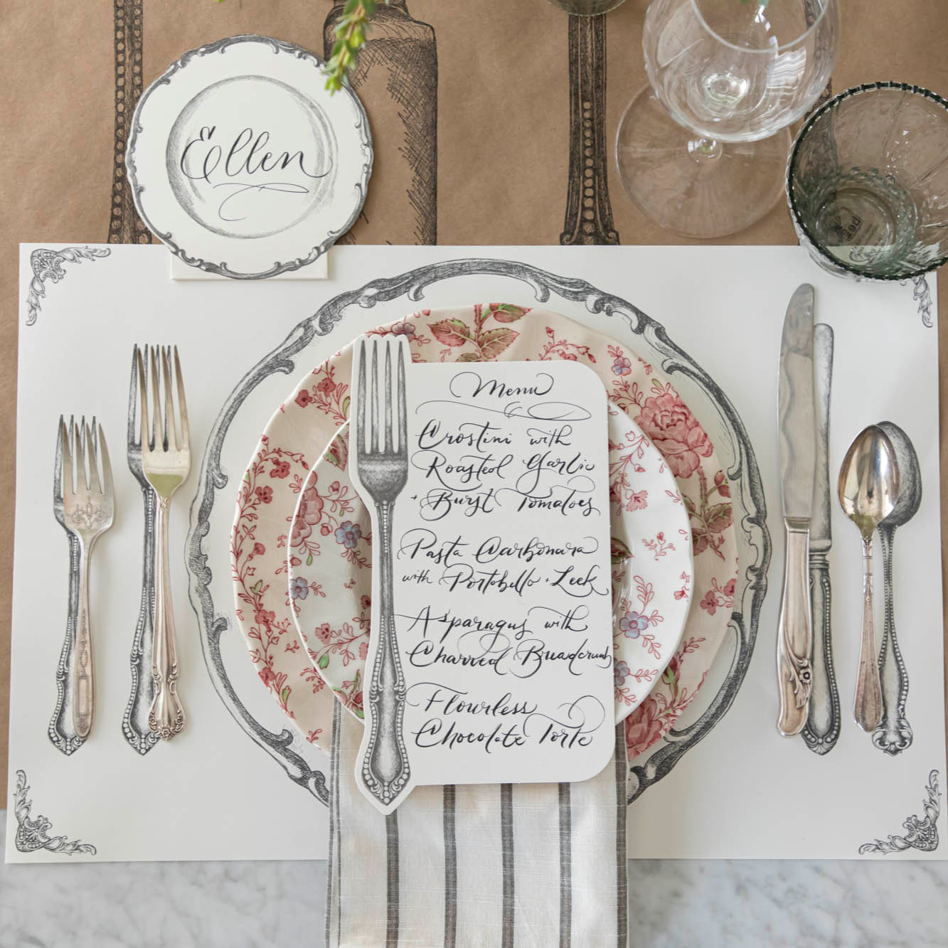 Vintage Fork Table Card with a menu written on it, resting on dinner plates on a table setting for one.