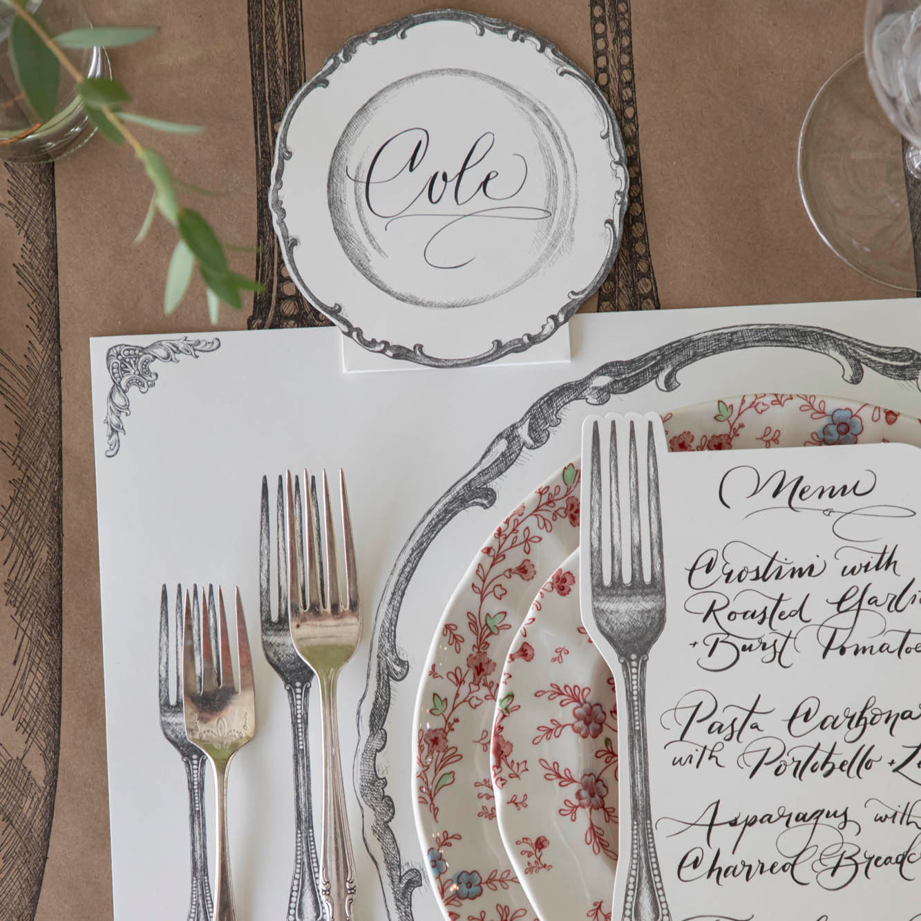 Vintage Plate Place Card with &quot;Cole&quot; written on it, laying flat behind a table setting for one.