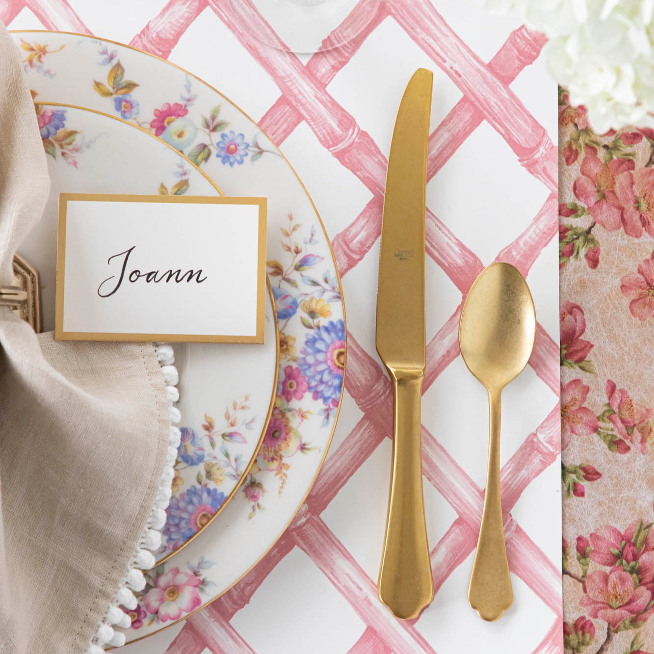 Gold Foil Frame Place Card with &quot;Joann&quot; written on it, resting on a set of dinner plates on a place setting.