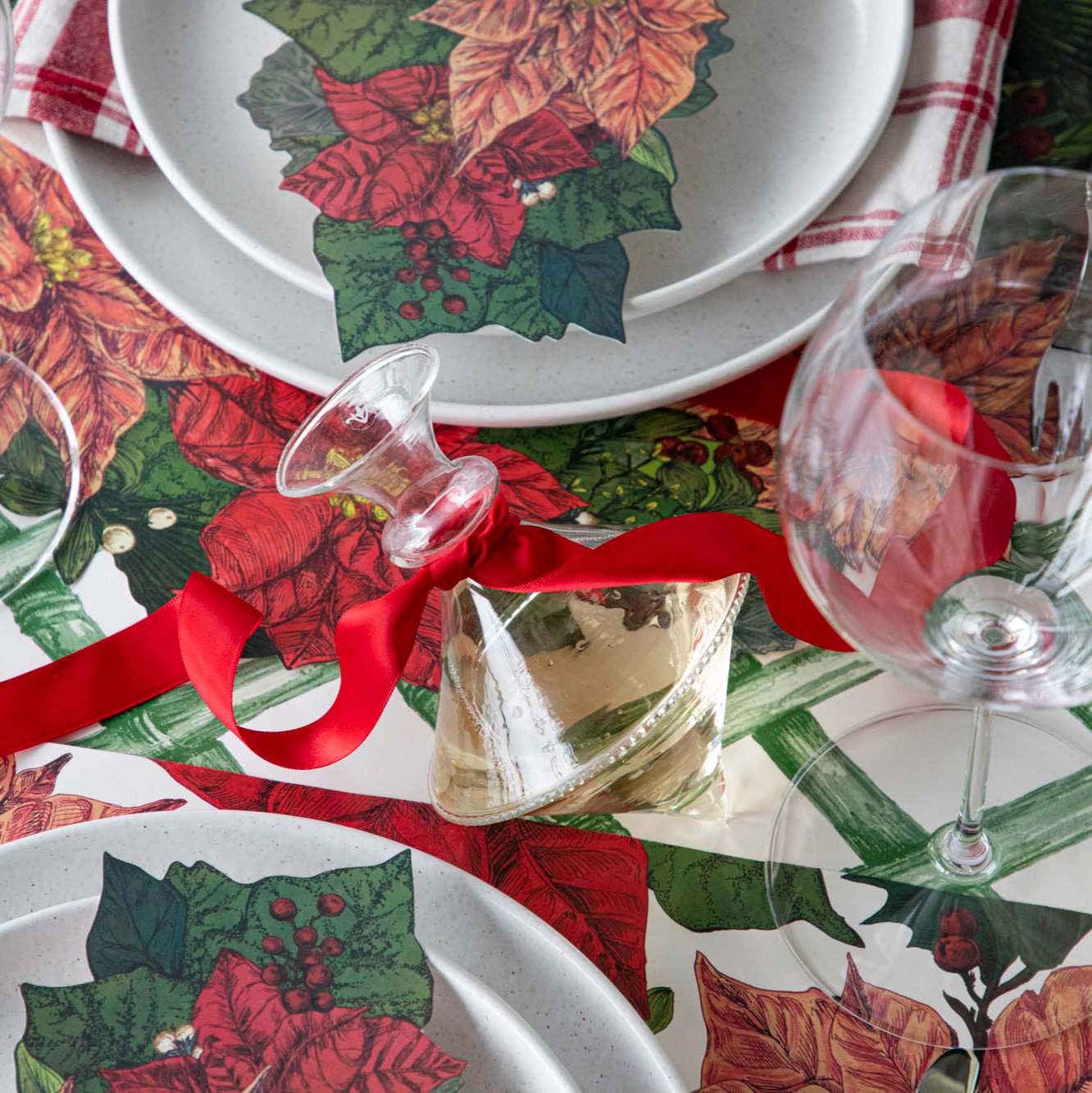 The Mouth Blown Clear Vase with wine and a red ribbon tied around the neck, on a Poinsettia themed table.