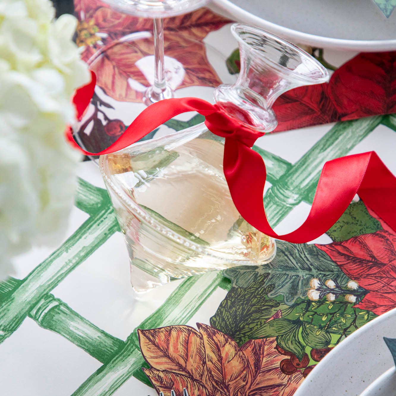 The Mouth Blown Clear Vase with wine and a red ribbon tied around the neck, on a Poinsettia themed table.