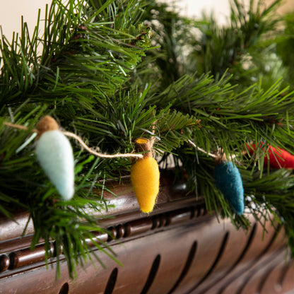 Felt String of Lights hanging on garland, propped on a mantle.