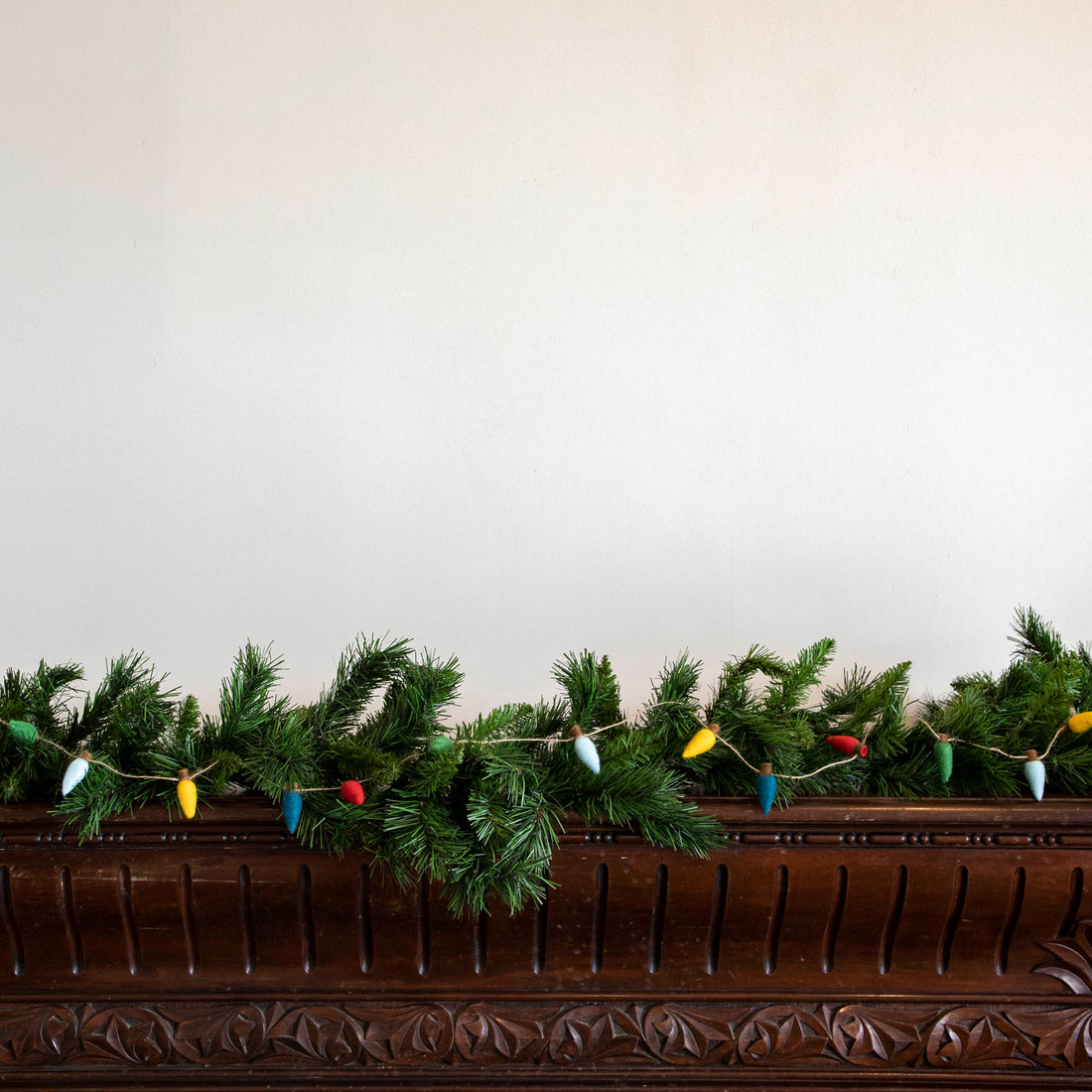 Felt String of Lights hanging on garland, propped on a mantle.