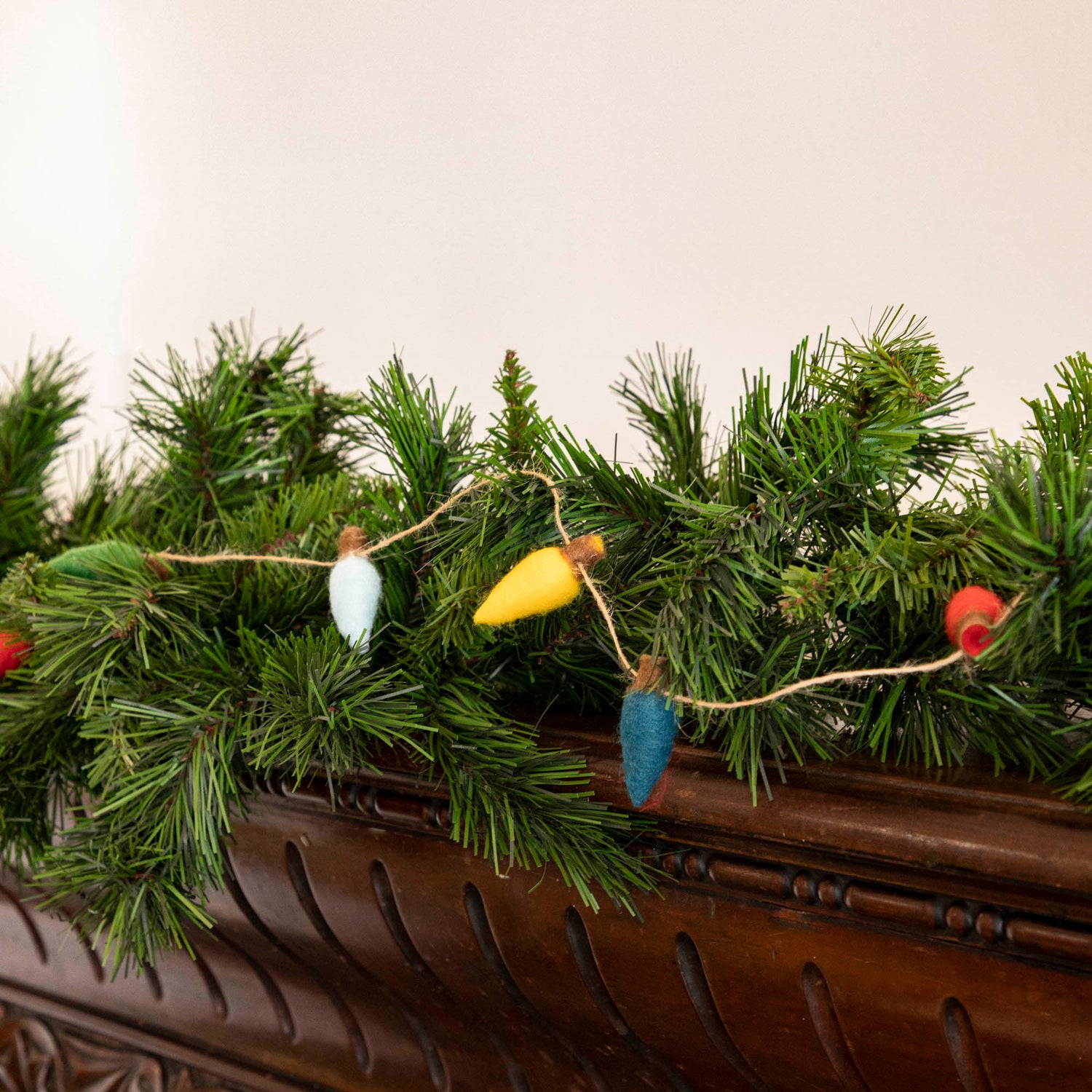 Felt String of Lights hanging on garland, propped on a mantle.