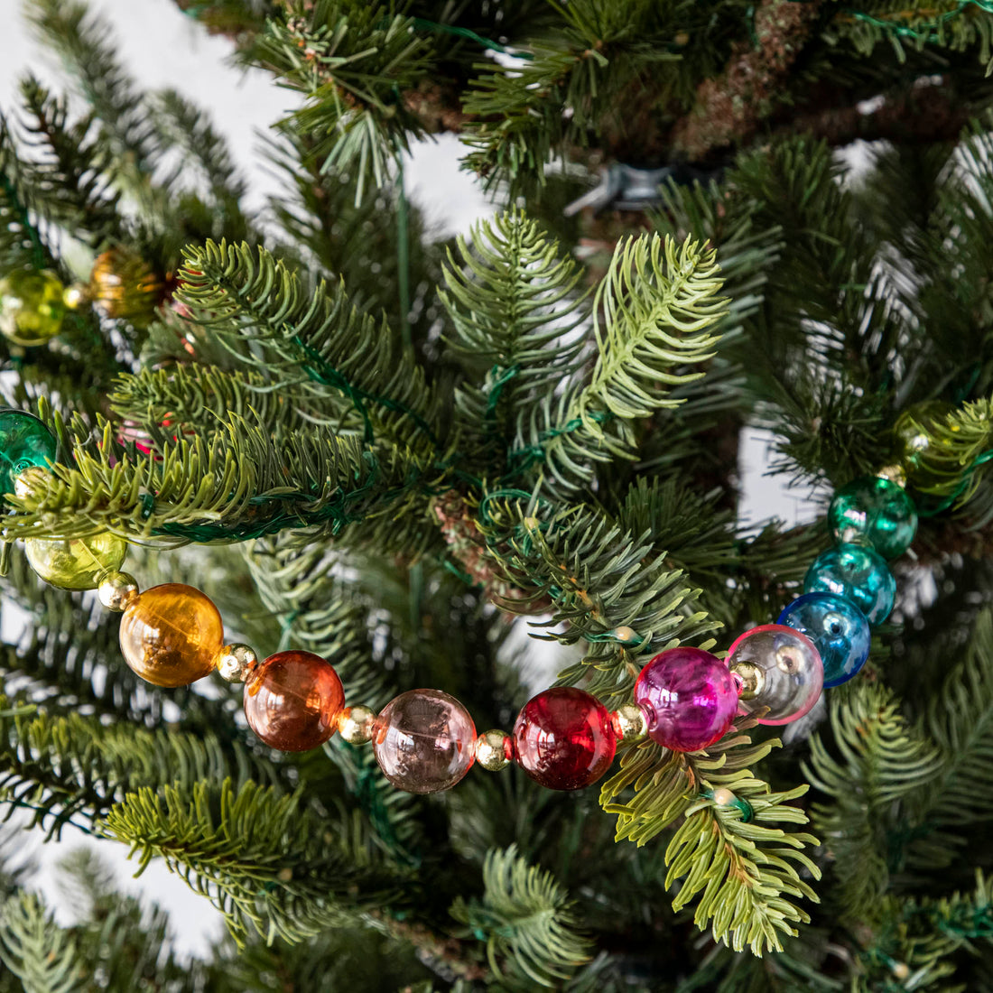 Blown Glass Rainbow Garland draped on a tree.