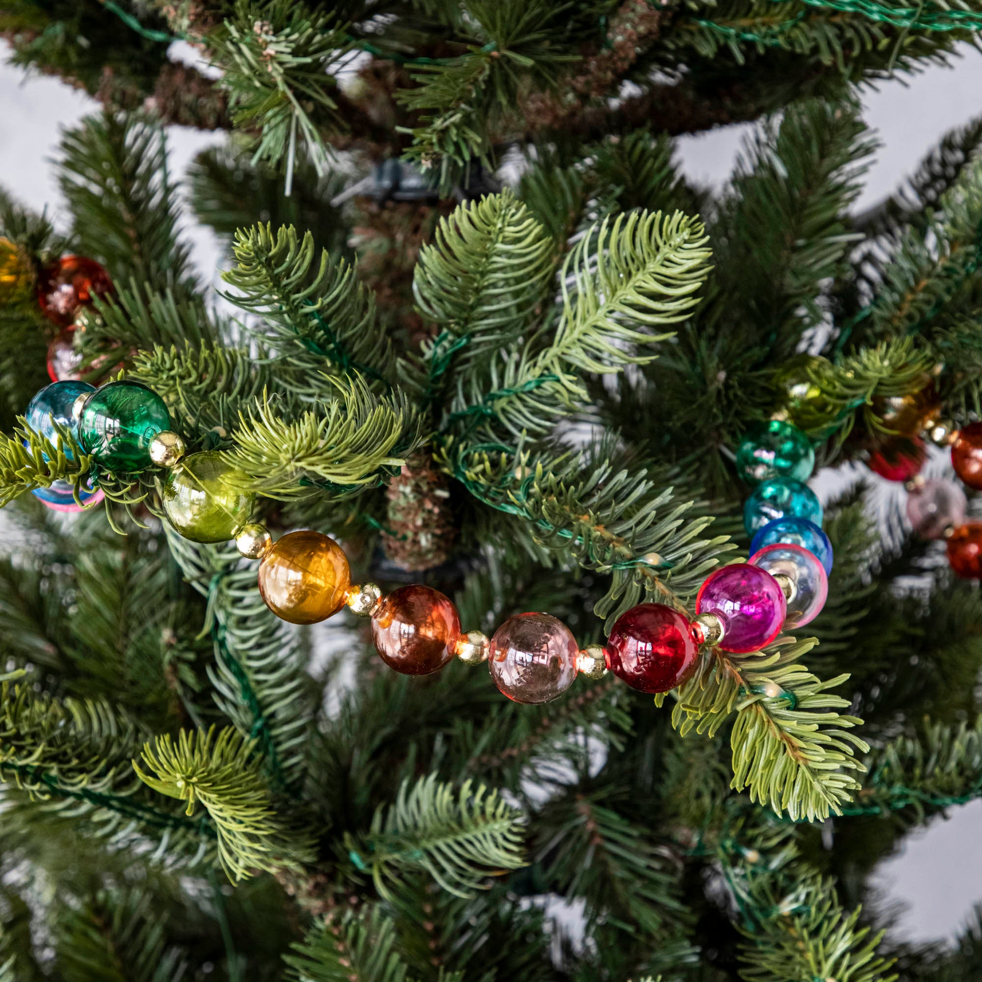 Blown Glass Rainbow Garland draped on a tree.