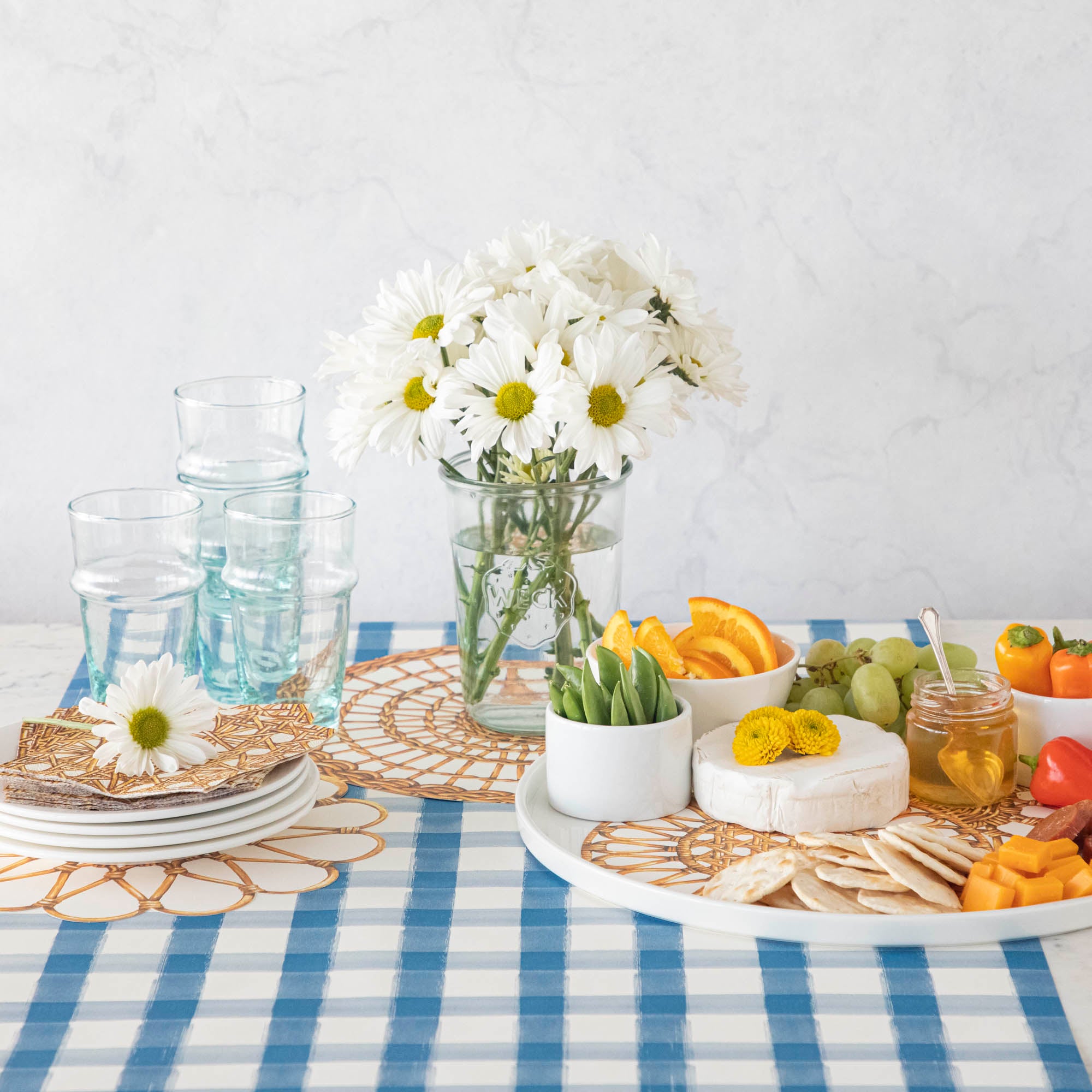 Rattan Weave Serving Papers on a platter under various food items, underneath a vase of flowers, and a stack of plates.