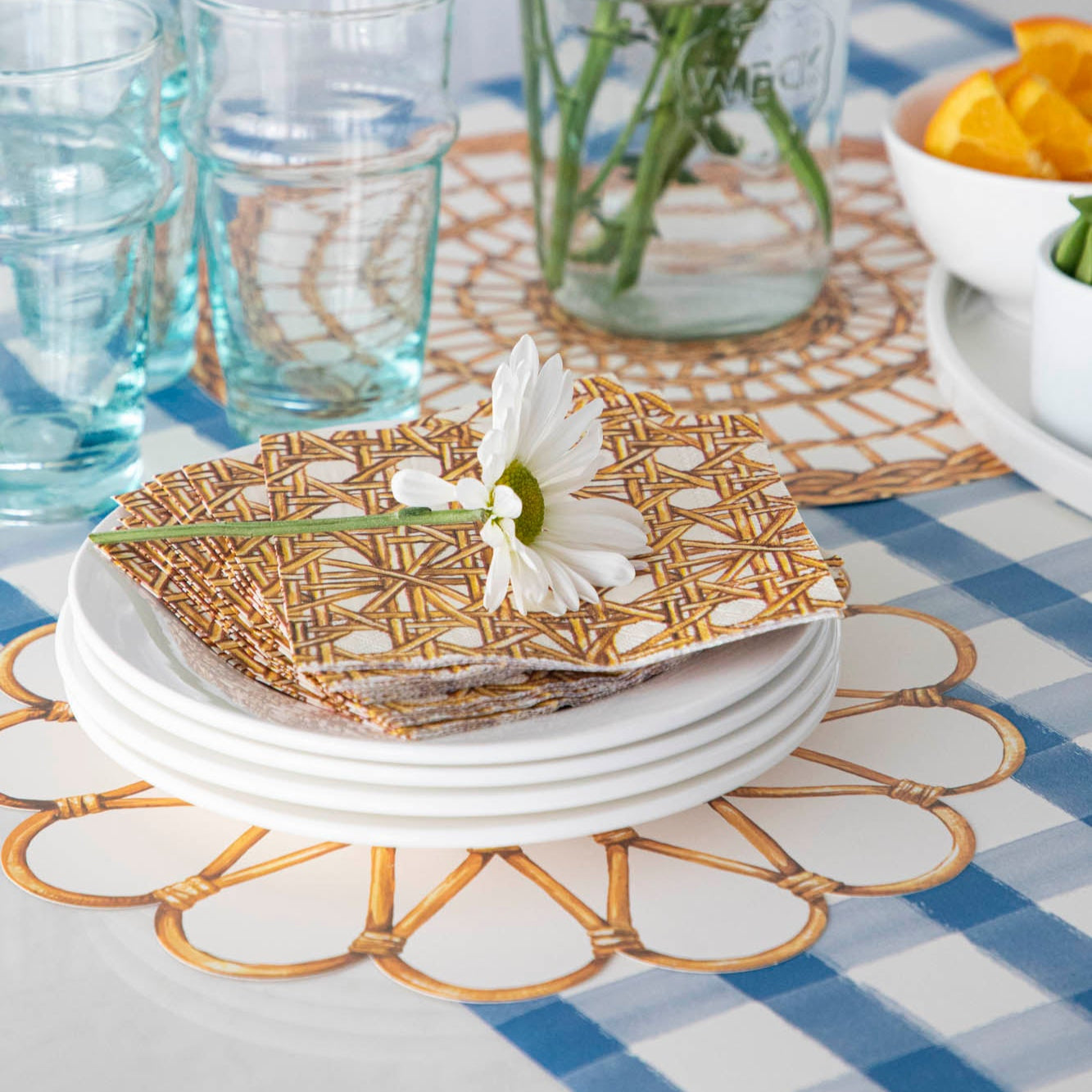 Rattan Weave Cocktail Napkins on a stack of plates, with a flower on top.