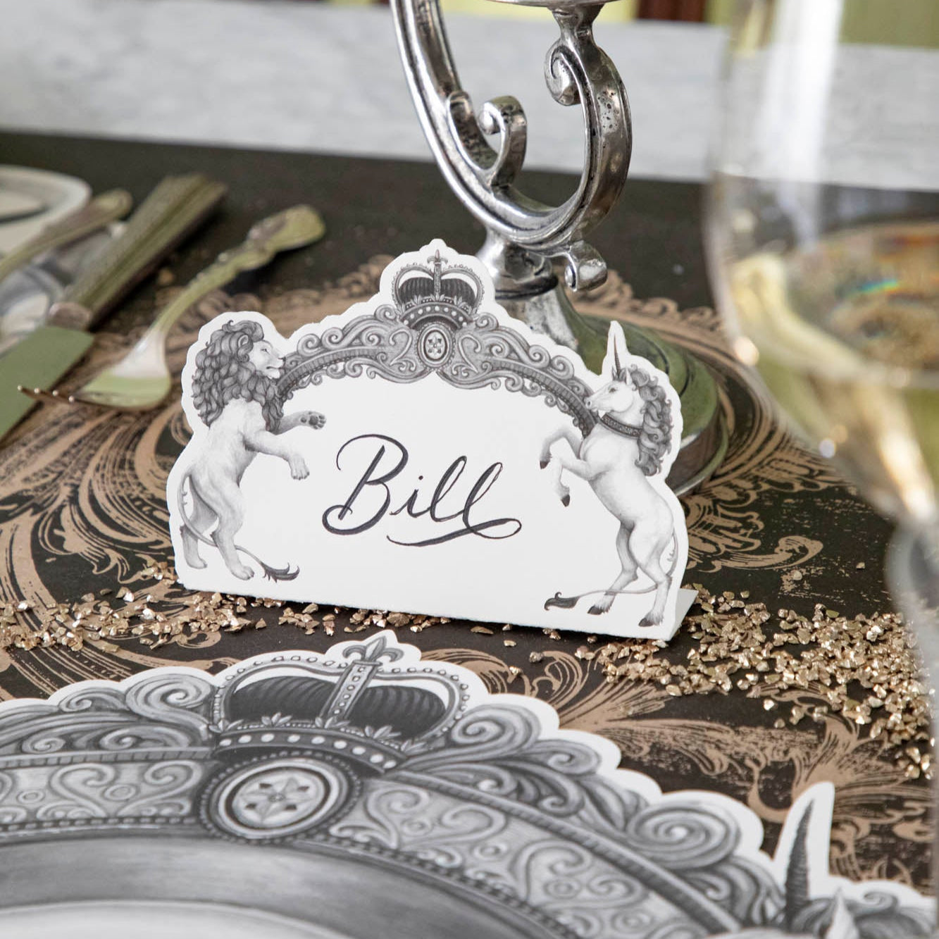 Regal Crest Place Card with &quot;Bill&quot; written on it, sitting in front of a candle stick holder.