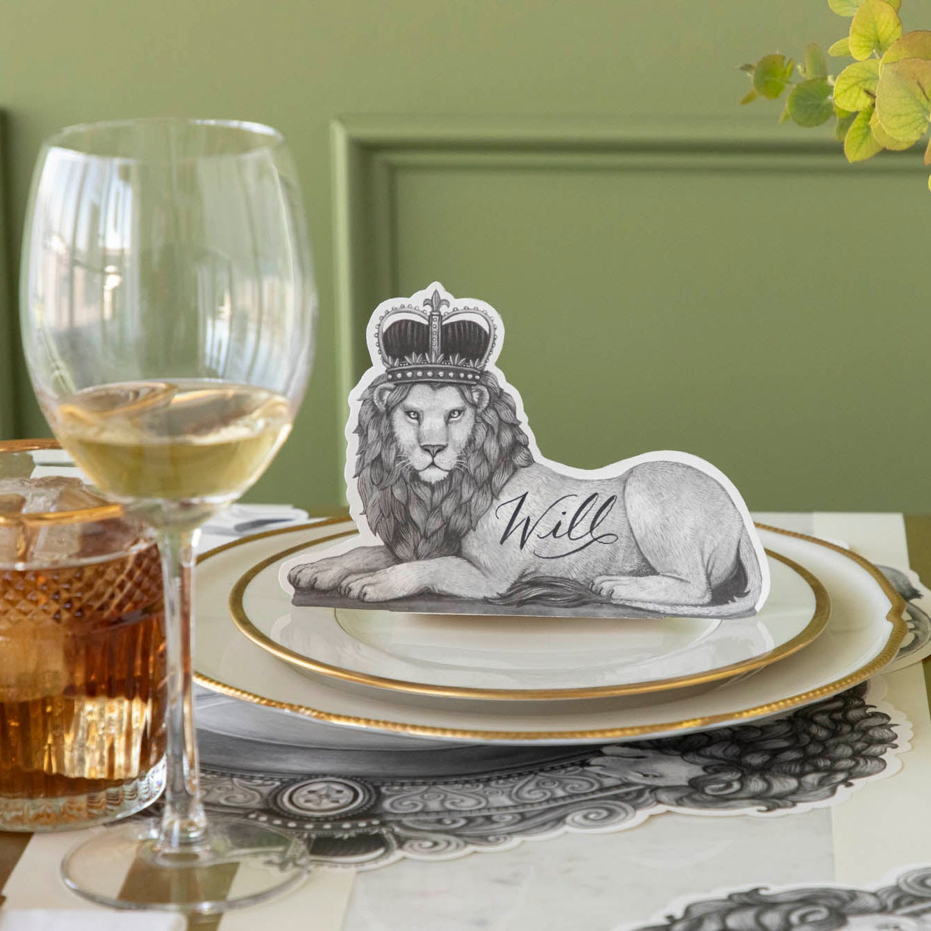 Regal Lion Place Card with &quot;Will written on it, sitting upwards on dinner plates.