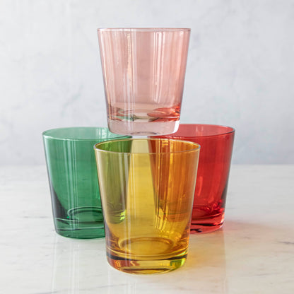 Three colorful Creative Co-Op lowball glasses in green, yellow, and red, with a pink glass stacked on top.