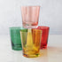 Three colorful Creative Co-Op lowball glasses in green, yellow, and red, with a pink glass stacked on top.