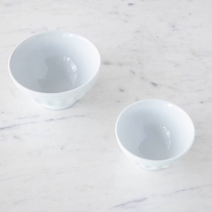 Two white BIA porcelain fluted bowls on a marble surface, one containing sprinkled chocolate bars and the other with chocolate pieces covered in sprinkles.