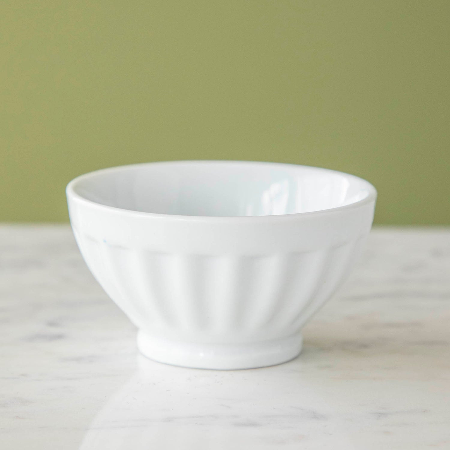 Two white BIA porcelain fluted bowls on a marble surface, one containing sprinkled chocolate bars and the other with chocolate pieces covered in sprinkles.