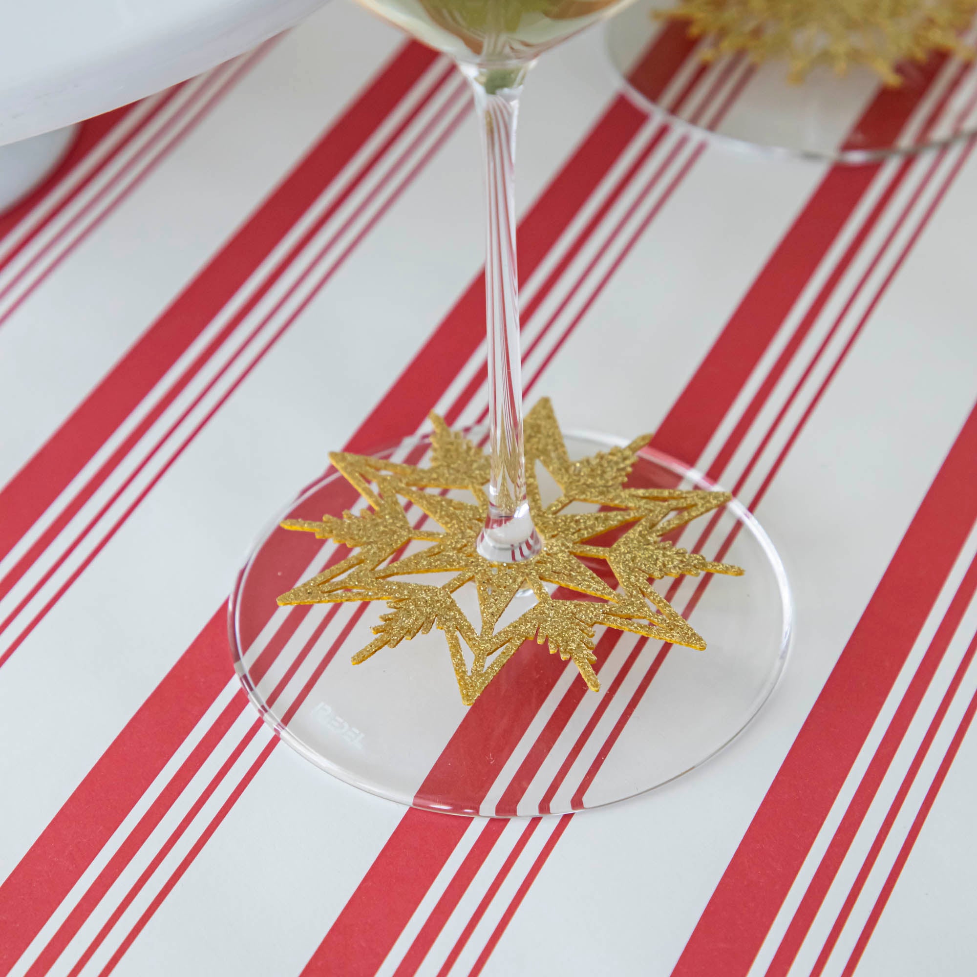 A Stemware Snowflake Collar around the base of a wine glass, on a Peppermint Stripe Runner.