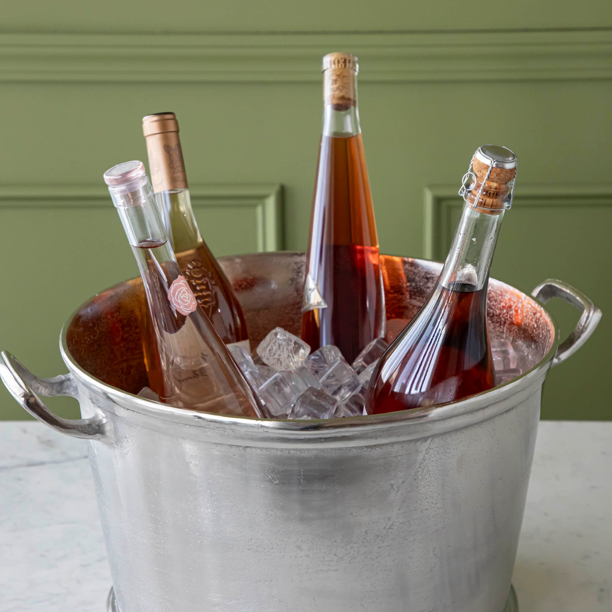 A Raw Aluminum Handled Planter/Wine Cooler filled with ice and wine bottles.