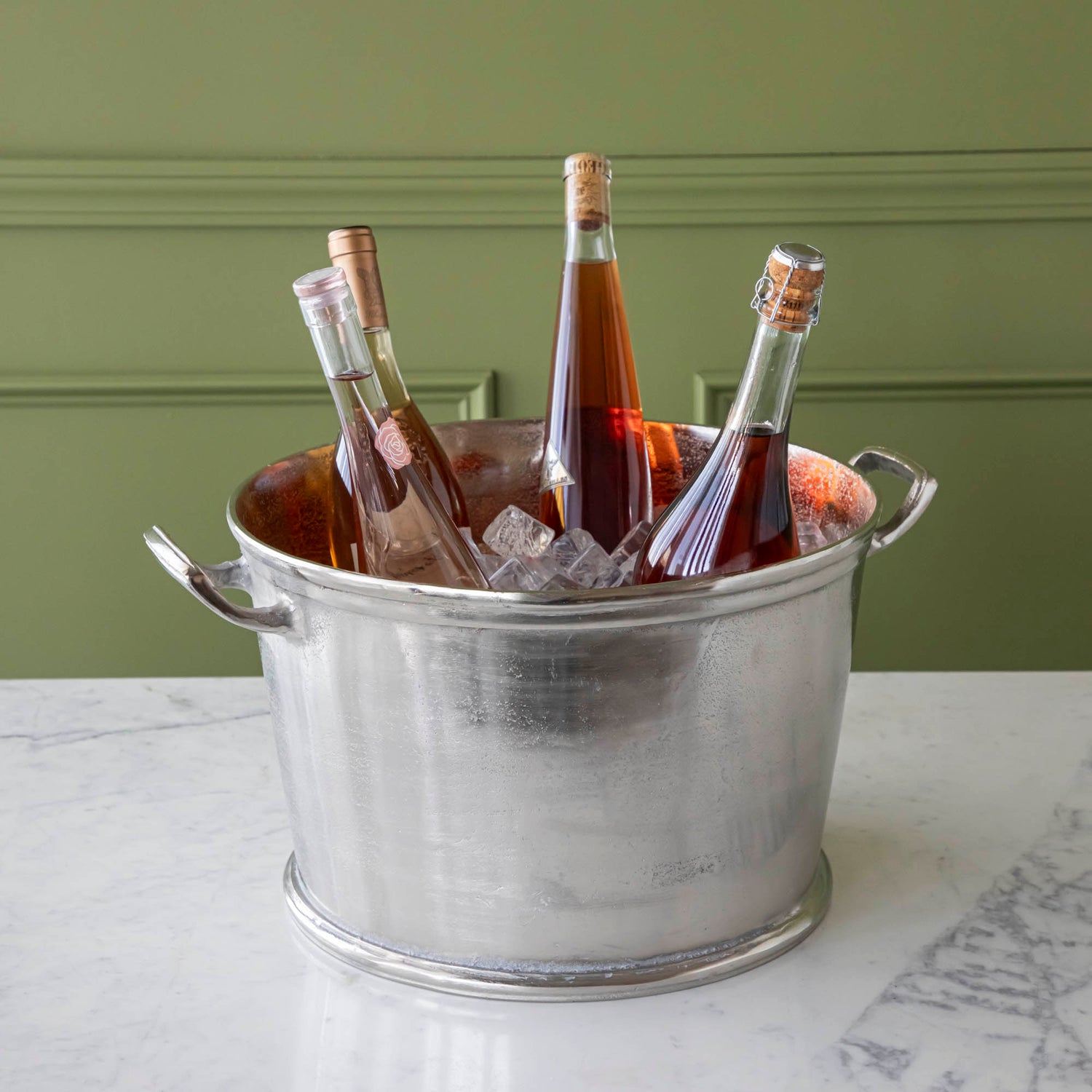 A Raw Aluminum Handled Planter/Wine Cooler filled with ice and wine bottles.