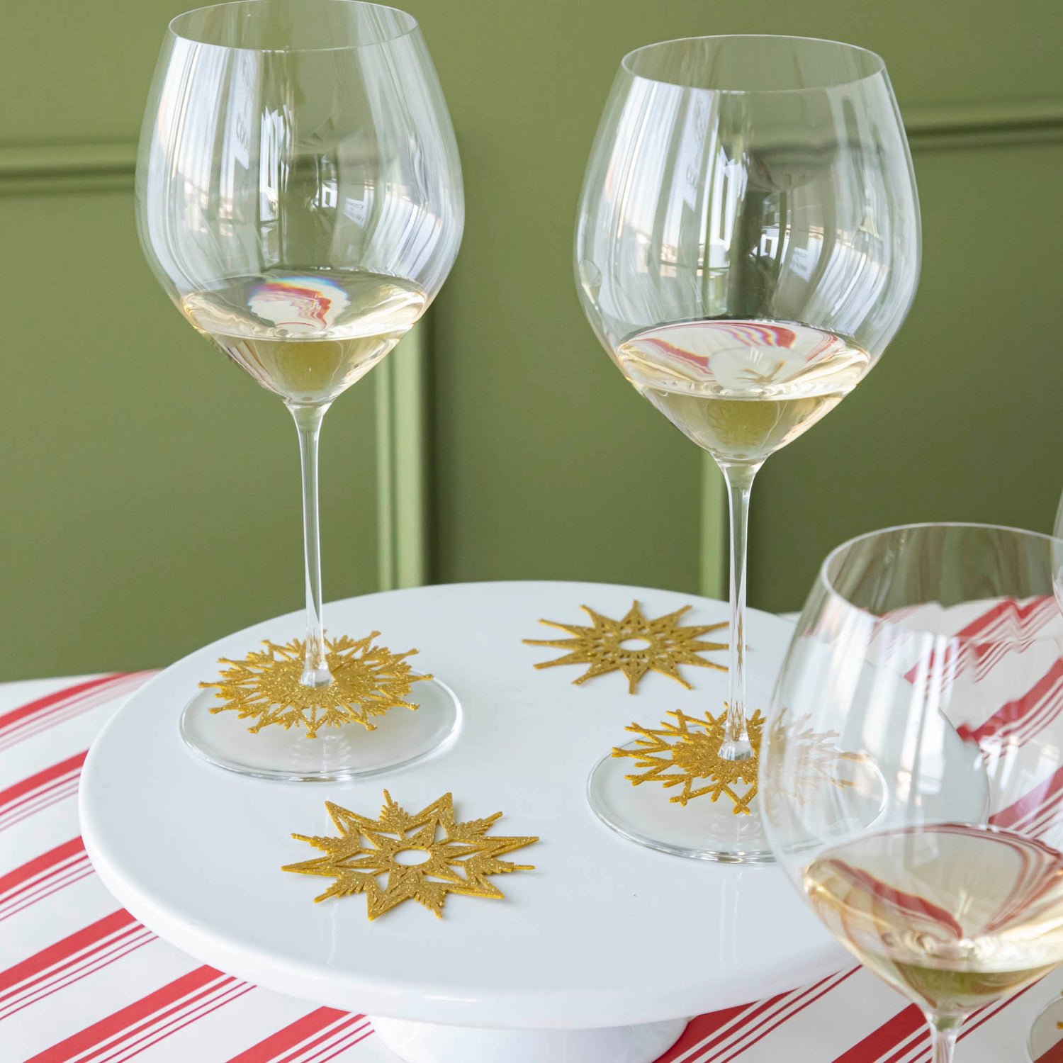 Two wine glasses with the Stemware Snowflake Collar around the base and two next to them on the cake stand.