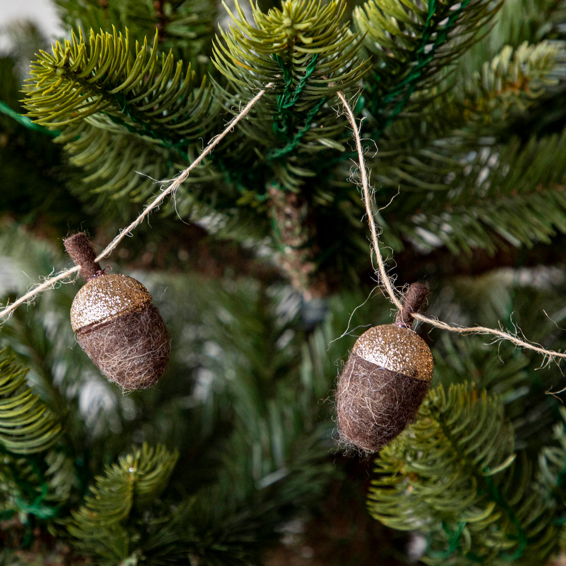 Close up of woolen acorn garland in a tree showing its glittered top 