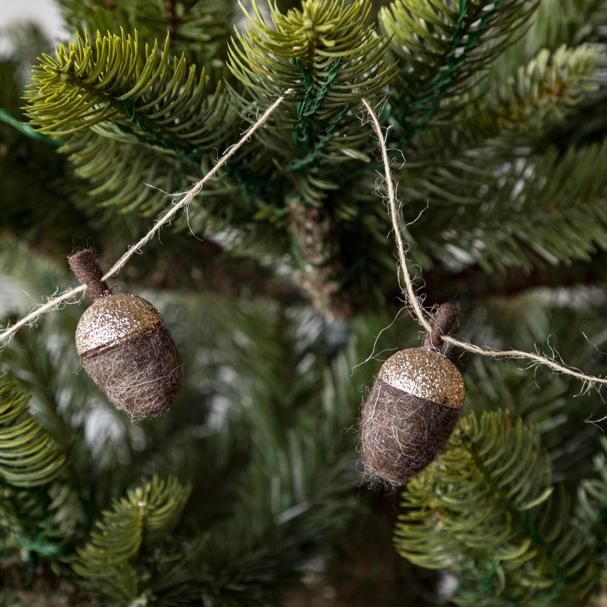 Close up of woolen acorn garland in a tree showing its glittered top 