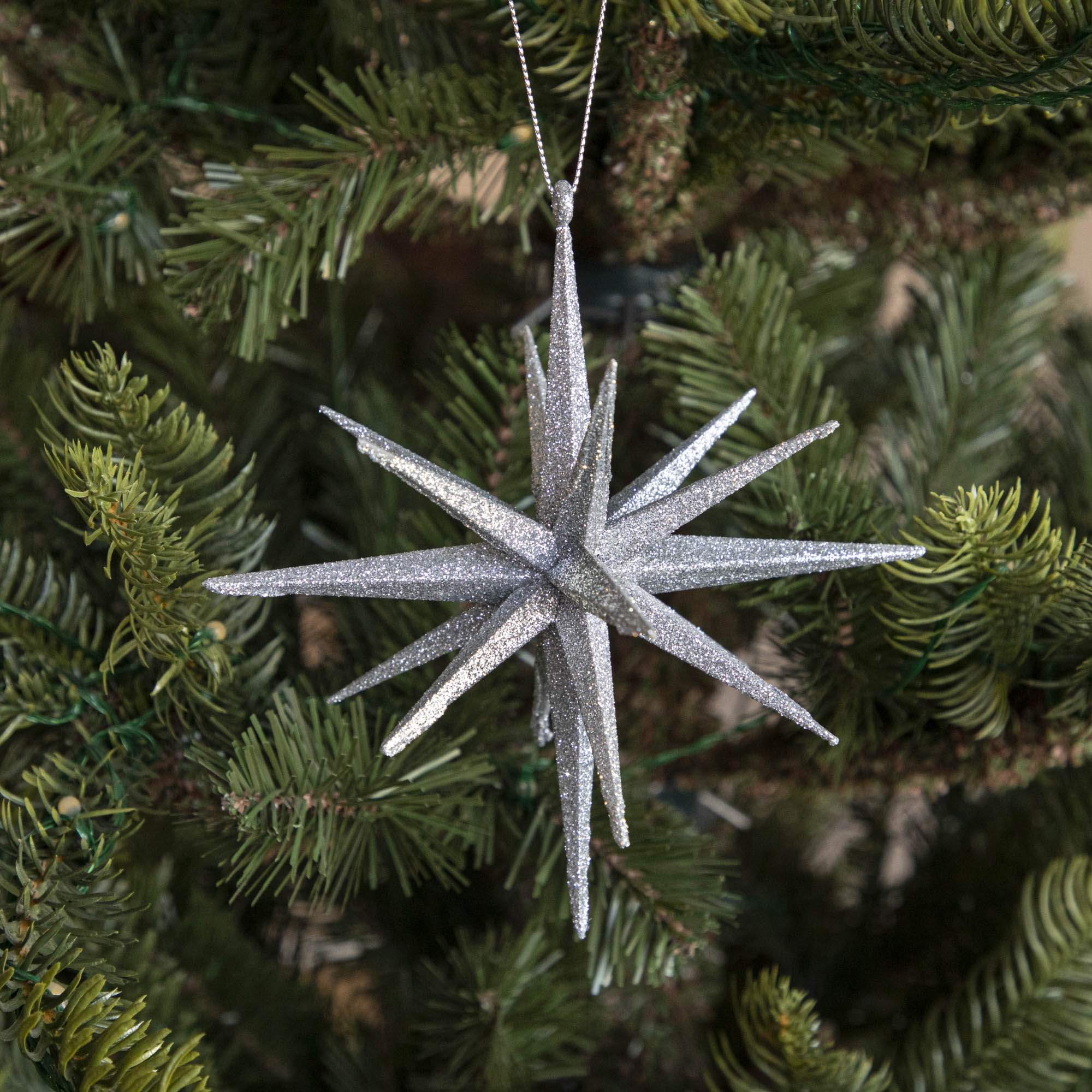 Silver Glitter 3-D star ornament hanging in tree