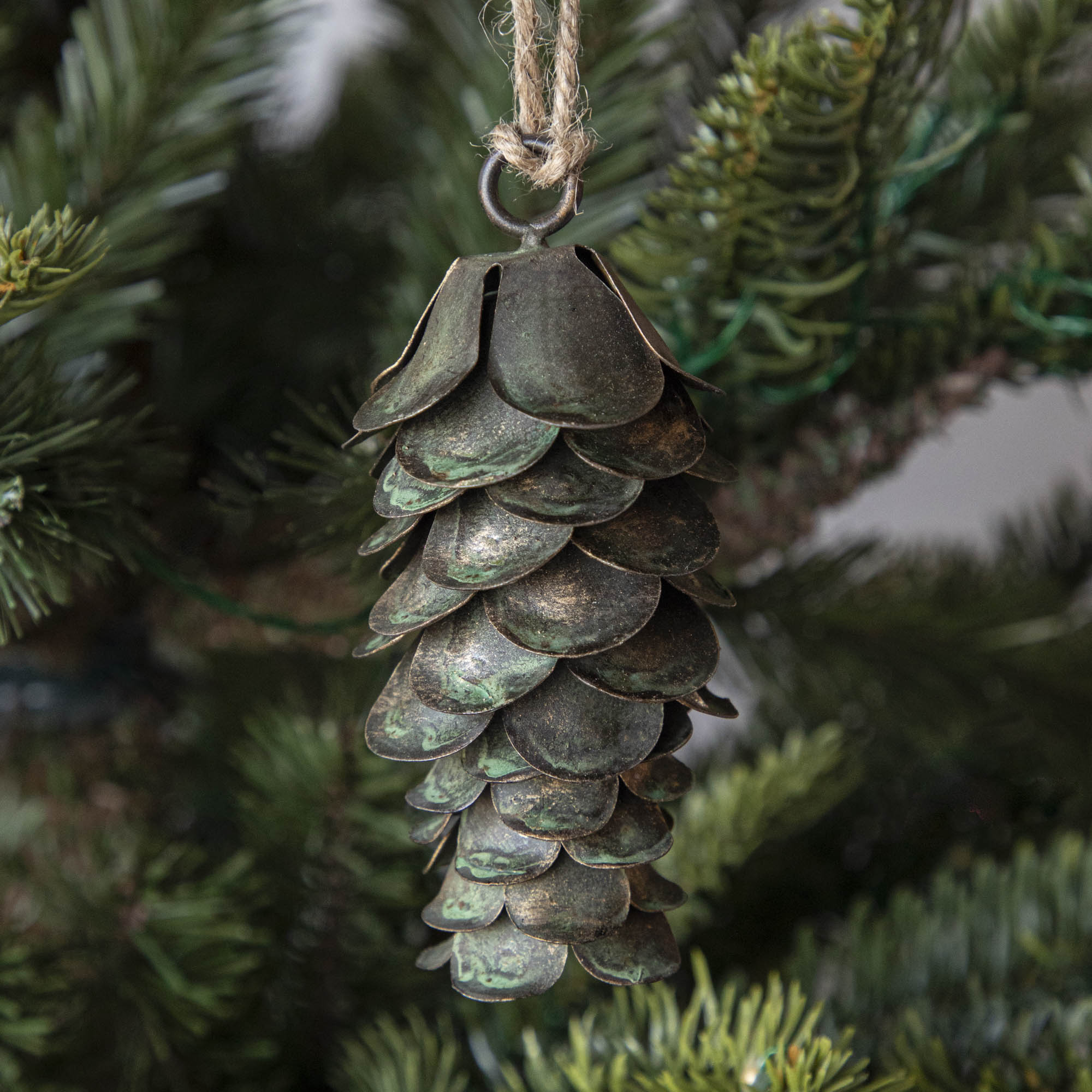 Metal Ornament in the shape of a pinecone hanging in a tree