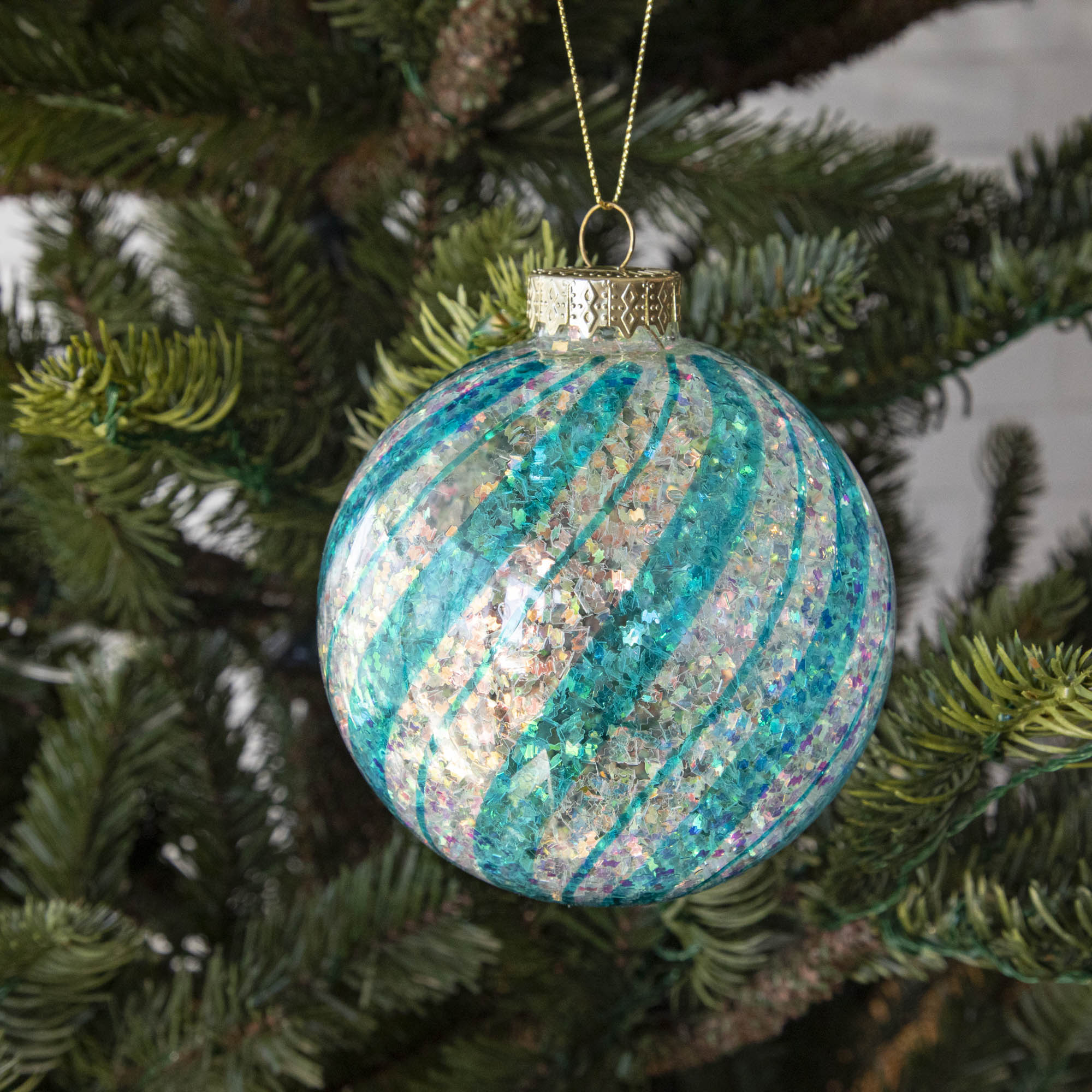 Blue &amp; White Candy Striped Glitter ball ornament hanging in a tree