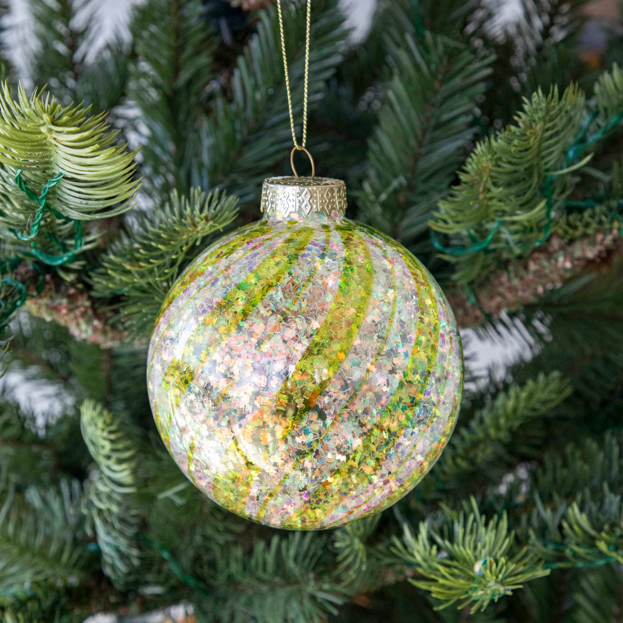 Green &amp; White Candy Striped Glitter ball ornament hanging in a tree