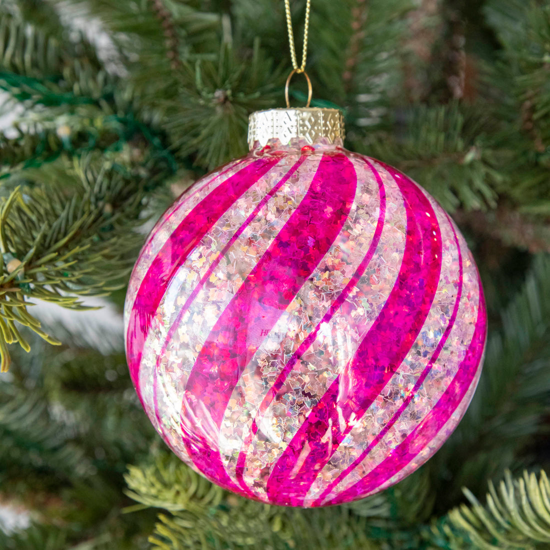 Pink &amp; White Candy Striped Glitter ball ornament hanging in a tree