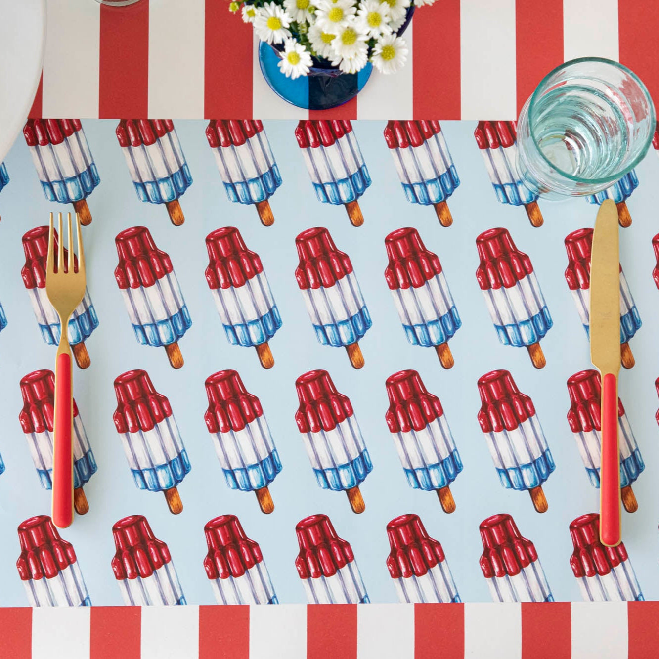 Rocket Pop Placemat with red &amp; gold flatware on top, on the Red Classic Stripe Runner.