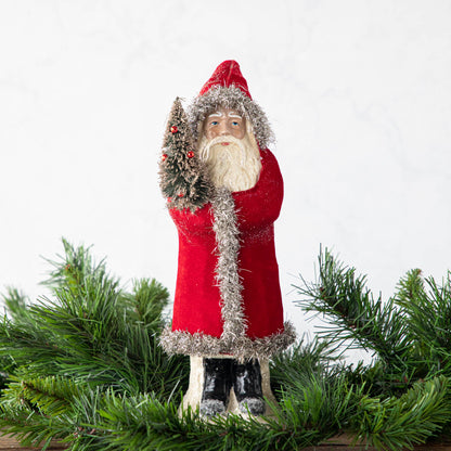 A 12&quot; Velvet Belsnickle figurine with a bright red velvet robe adorned with tinsel trimming and glitter, holding a tree.