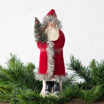 A 12&quot; Velvet Belsnickle figurine with a dark red velvet robe adorned with tinsel trimming and glitter, holding a tree.