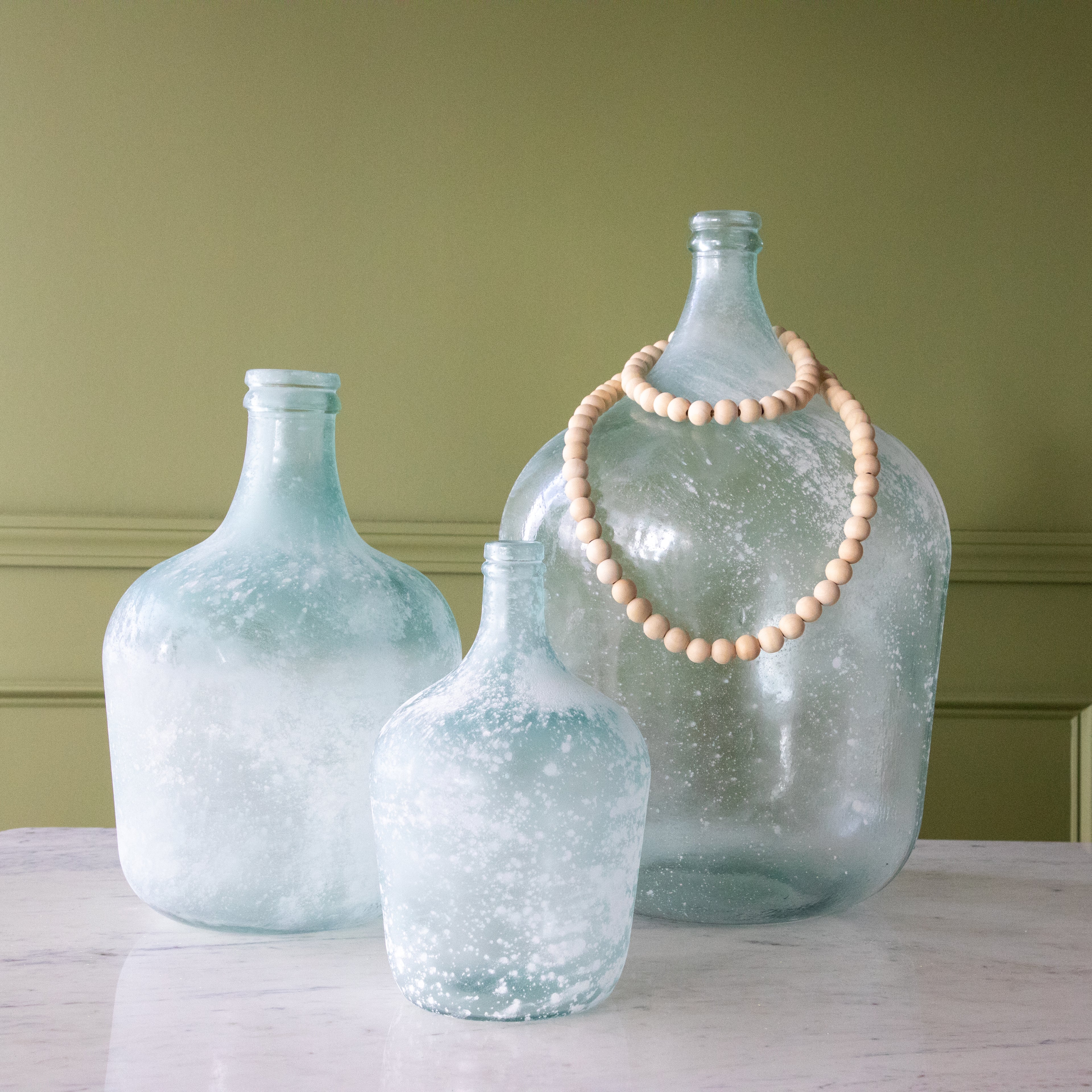 Frosted Seafoam Cellar Bottles in small, medium and large with beads around the large bottle.