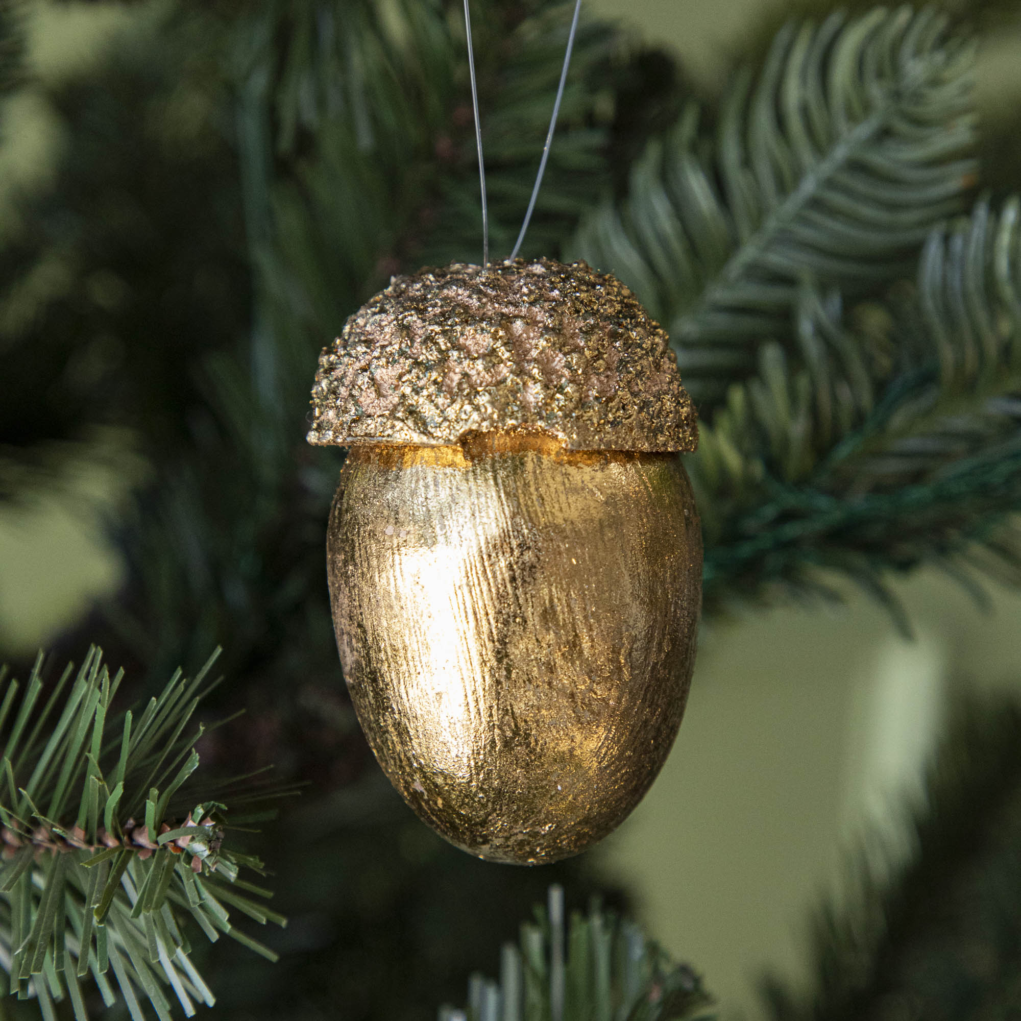 gold acorn ornament hanging in a tree