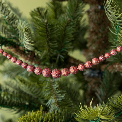 red sparkly ball garland hanging in a tree