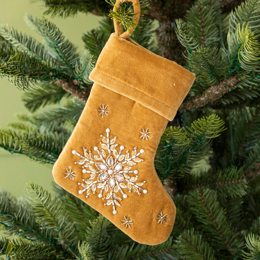 Mustard Velvet Stocking ornament hanging in a tree