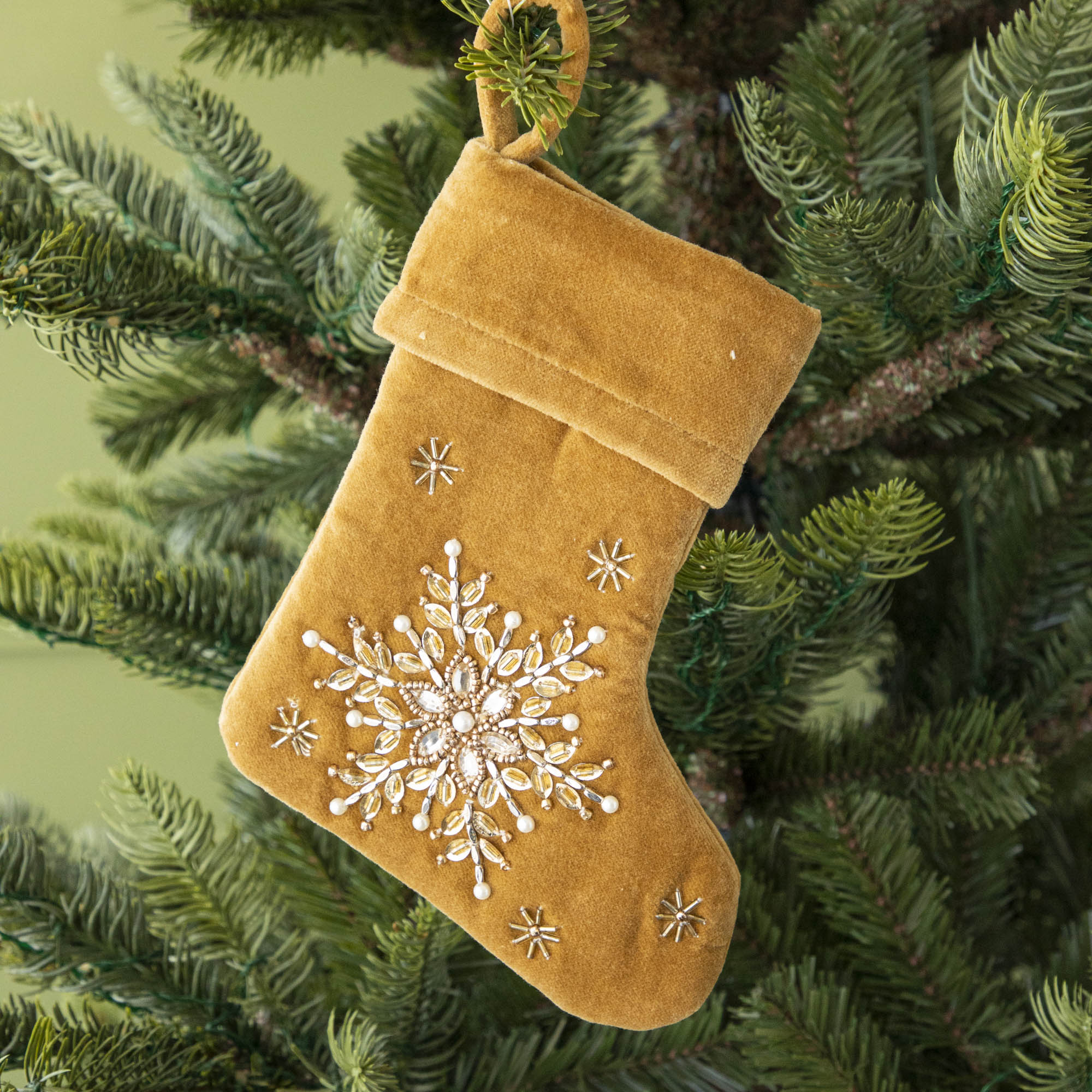 Mustard Velvet Stocking ornament hanging in a tree