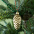 shiny gold pinecone ornament hanging in a tree