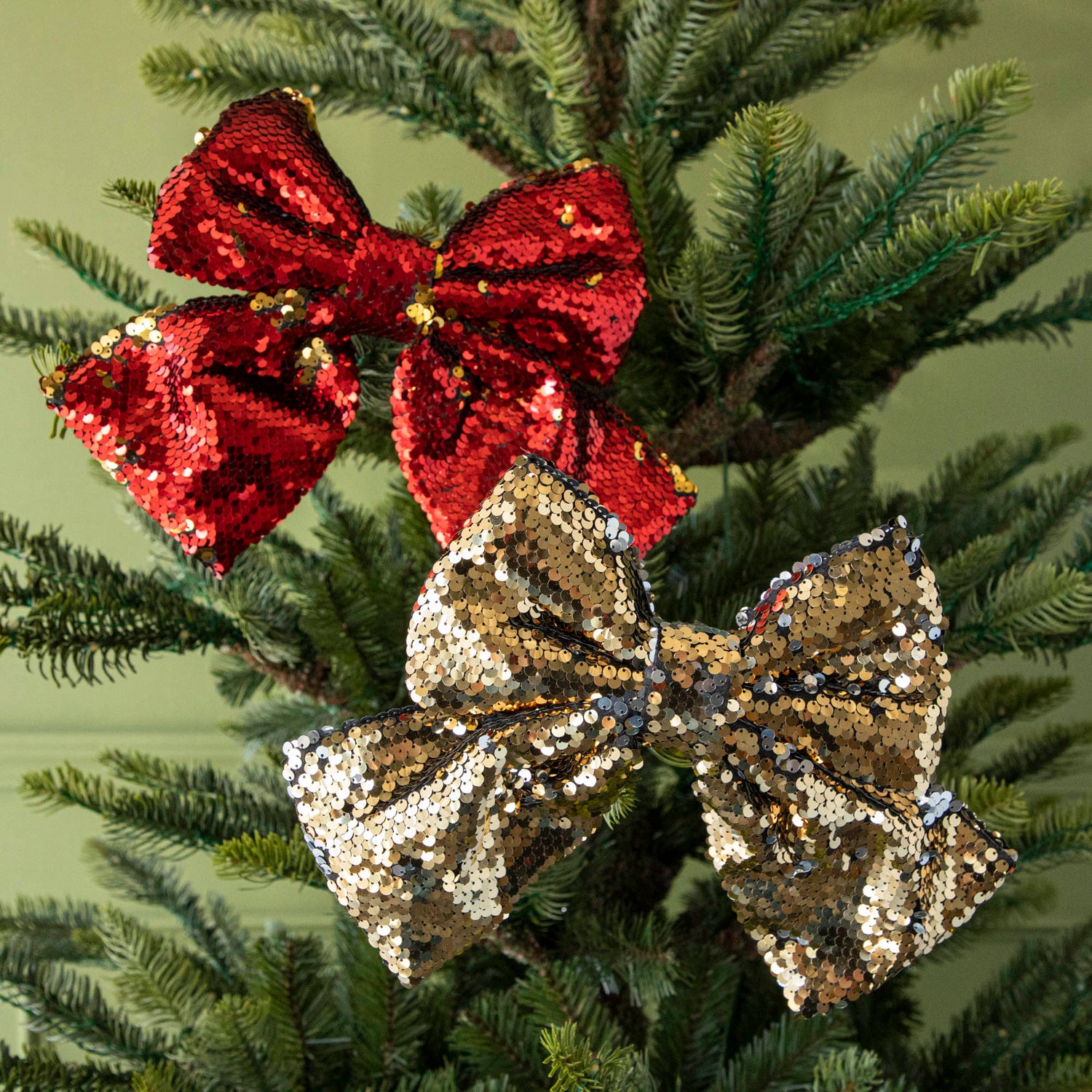 The red and gold Puffy Sequin Bows with Clip, clipped to a tree.