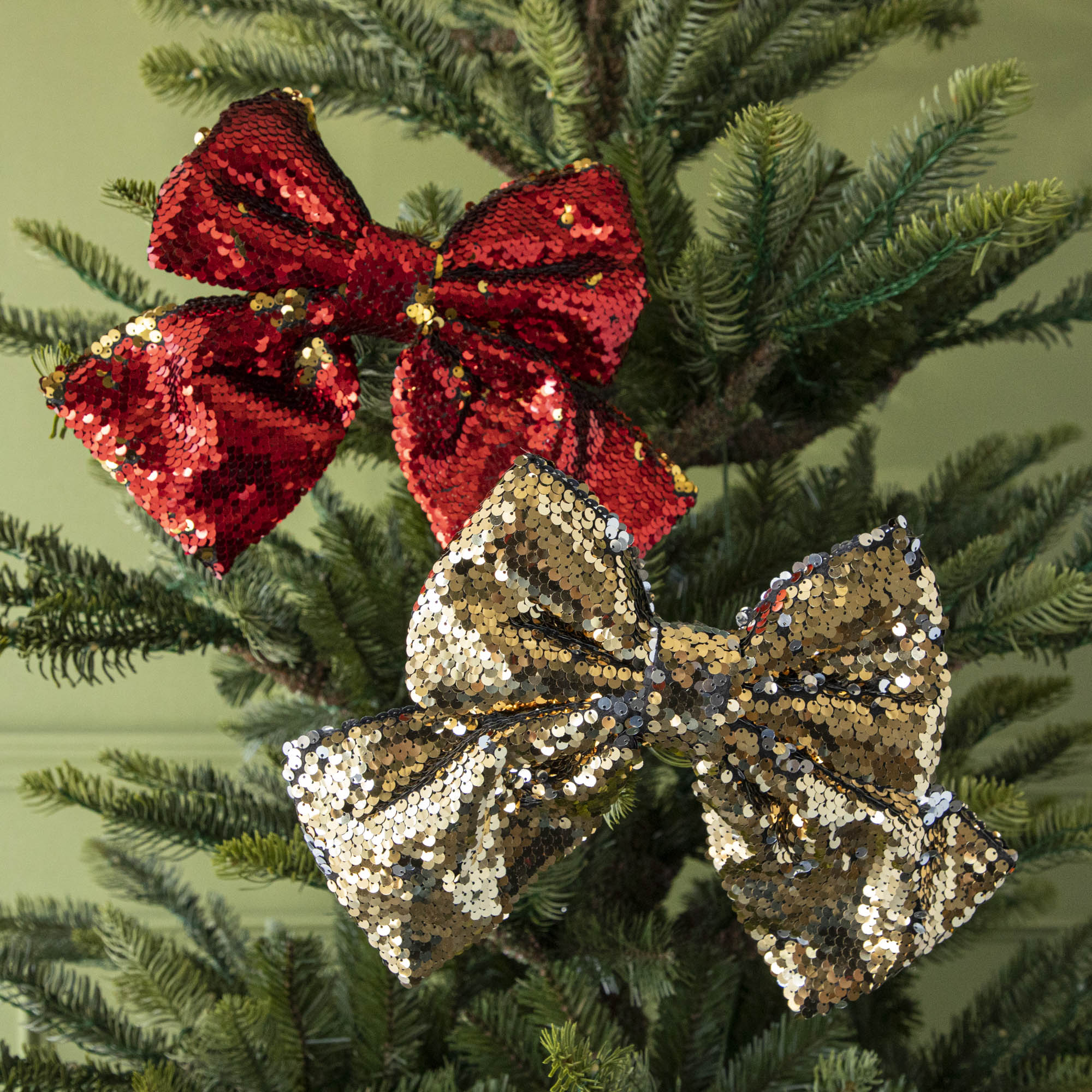 Red sequin bow ornament and gold sequin bow ornament in tree