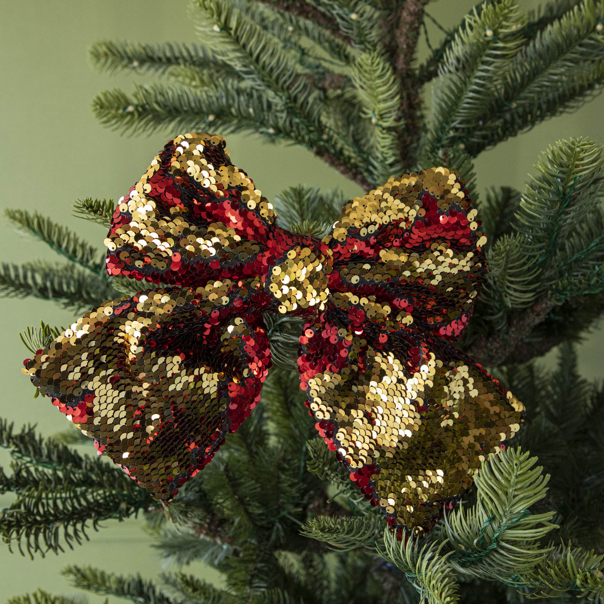 A close up of the red Puffy Sequin Bow Ornament showing its reversible red to gold sequins.