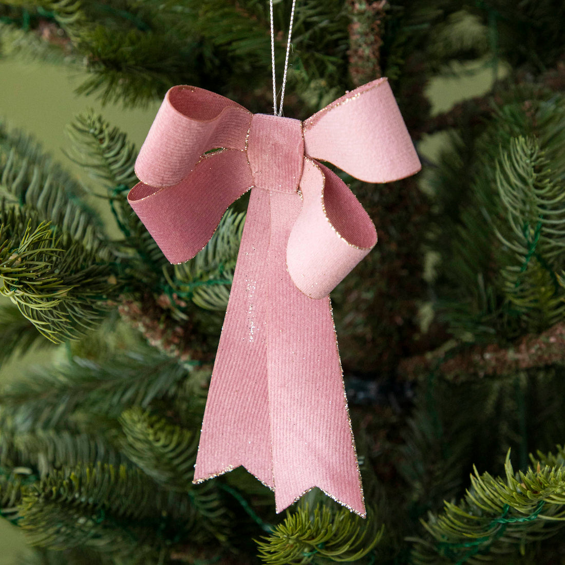 close up of pink bow ornament hanging in a tree