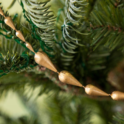 Close up of Gold Drop Garland draped on a tree.