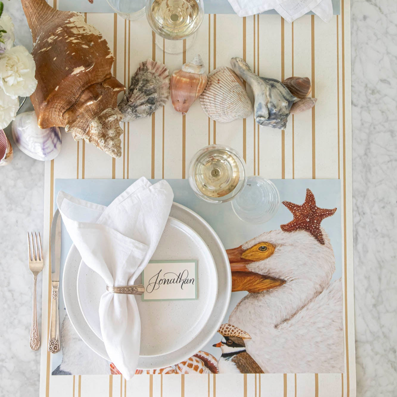 A coastal table featuring the Shorebirds Placemat under a place setting on the Antique Gold Stripe Runner.