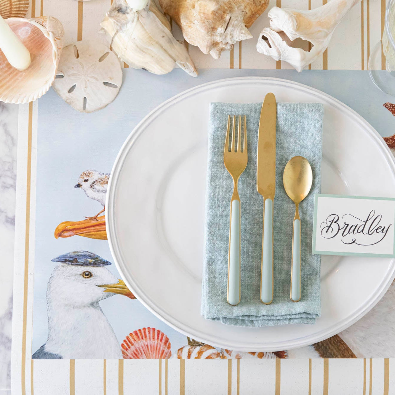 A coastal table setting with the Shorebirds Placemat under a place setting.