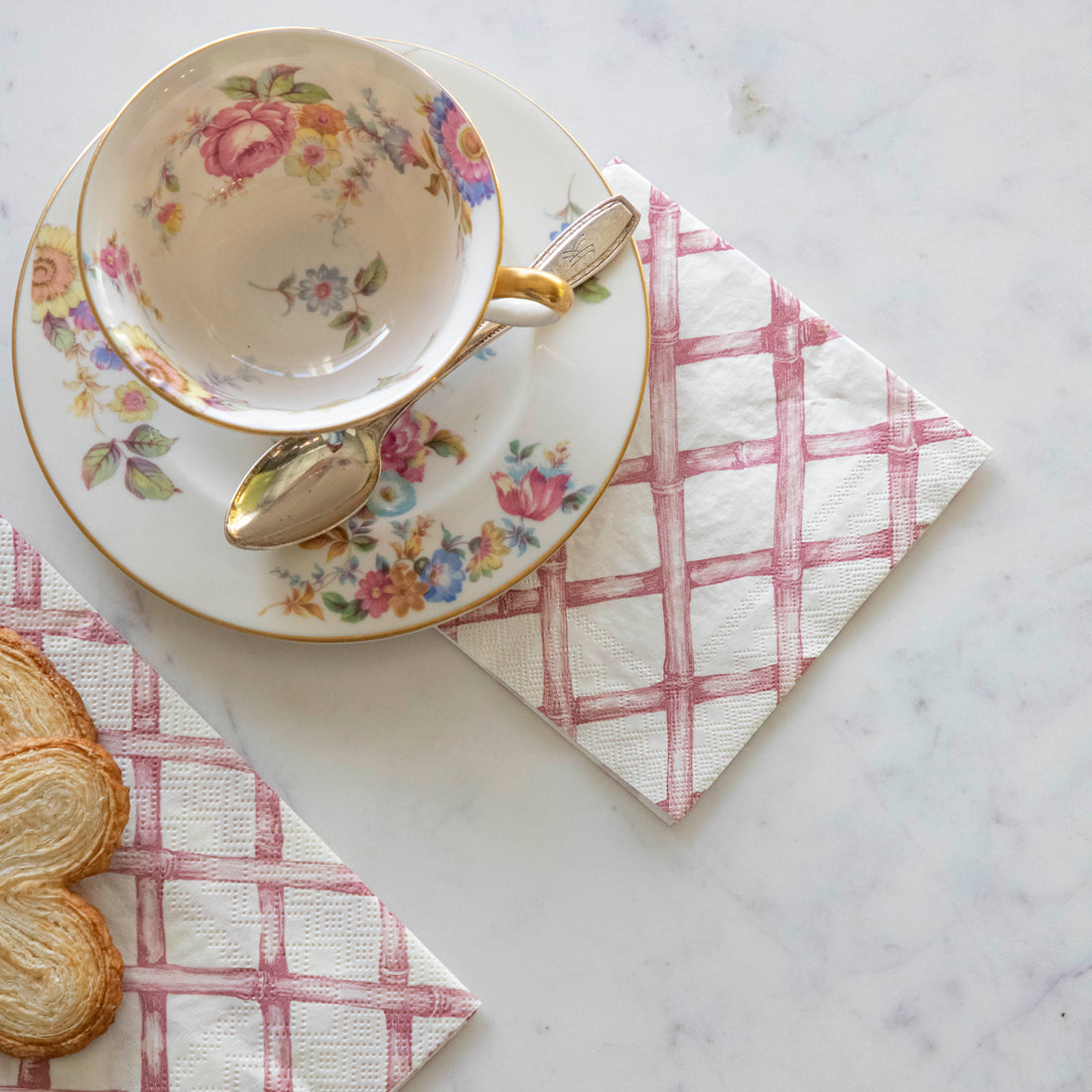 Pink Lattice Cocktail Napkin slightly underneath a tea cup and saucer.