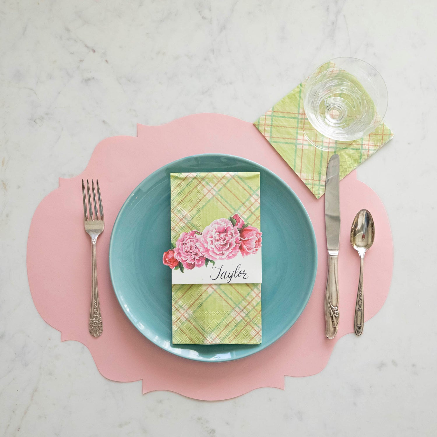 A place setting with the Bright Green Plaid Guest Napkin on top of the plate with the Bright Green Cocktail Napkin under a glass.