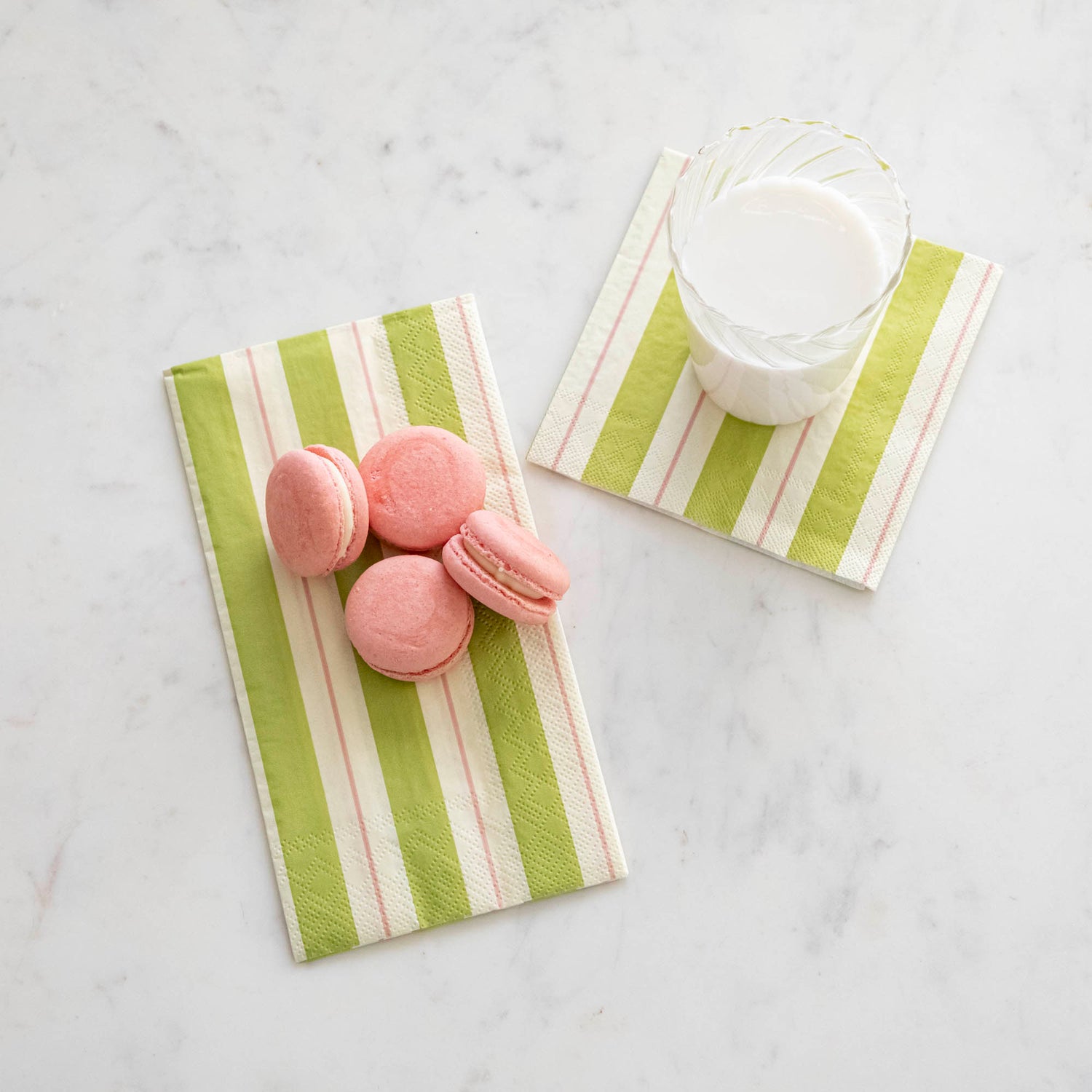 Green &amp; Pink Awning Stripe Napkins with a glass of milk and macaroons on top.