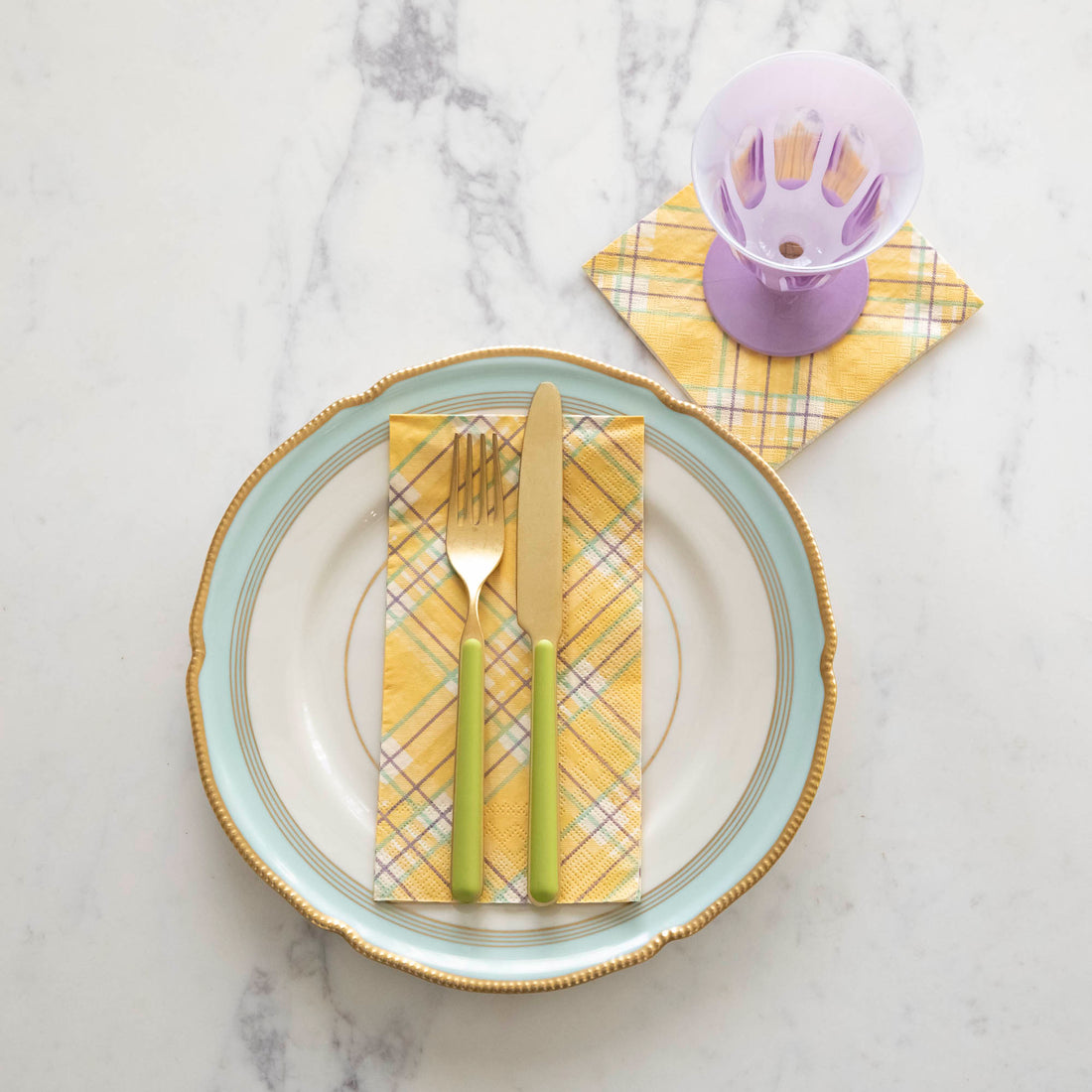 Yellow Plaid Guest Napkin on a plate with flatware on top and the yellow plaid cocktail napkin under a glass.