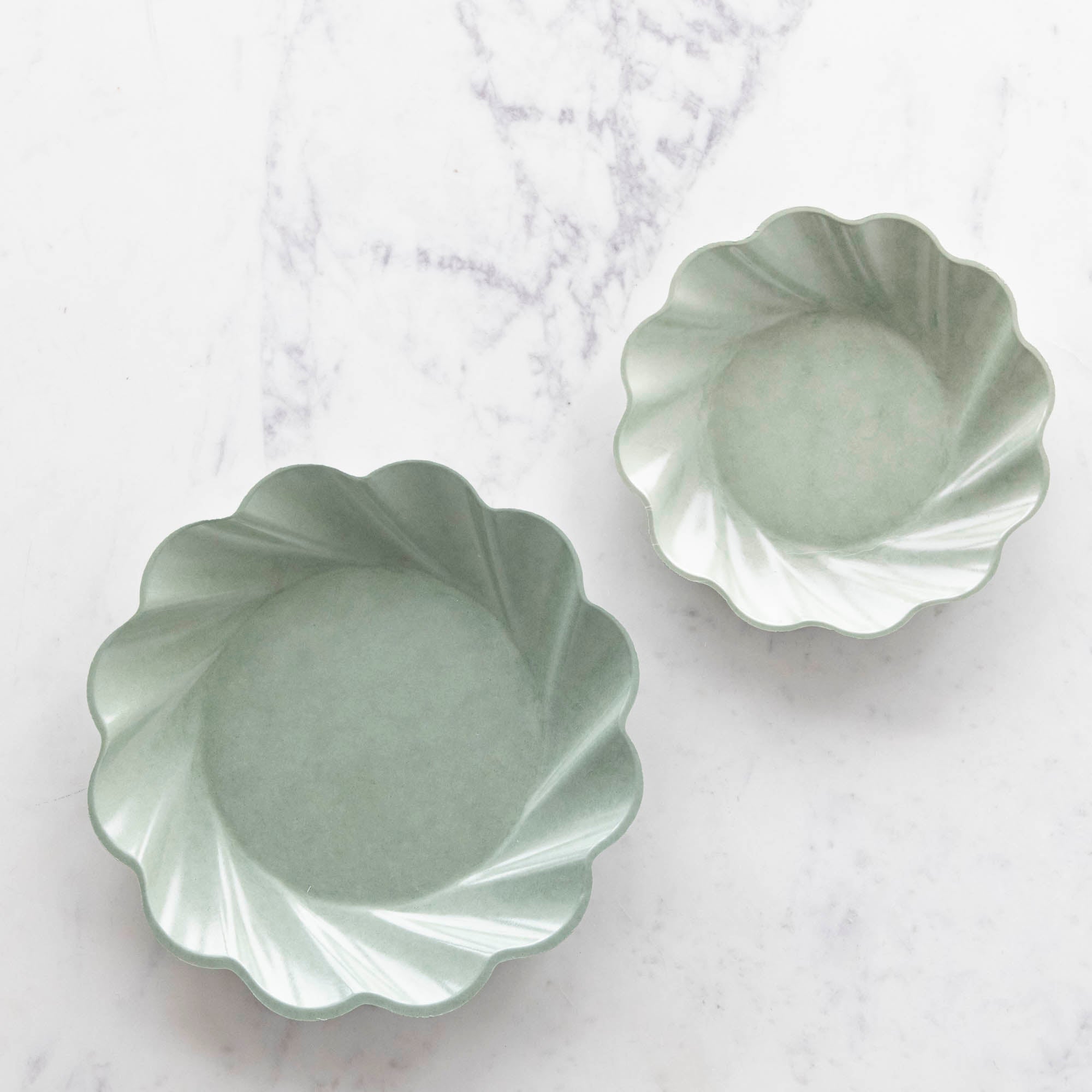 Three sturdy, Sophistiplate Wavy Eco Sage Plates stacked on top of each other.